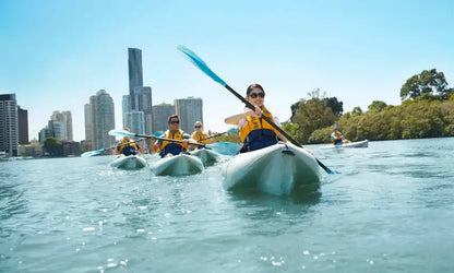 People kayaking on a river with a city skyline in the background